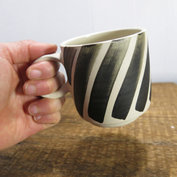The same cup being picked up by a hand, two fingers holding the handle.