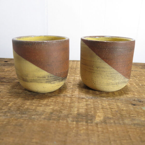 Two cups made with red stoneware and a yellow decoration.
