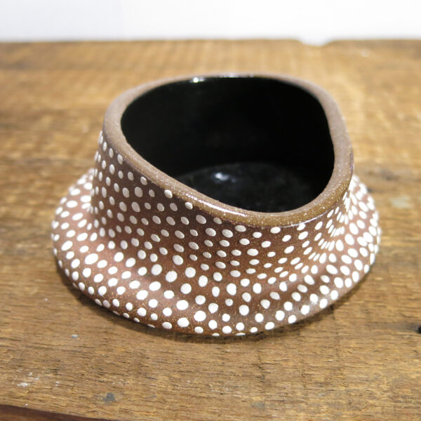 Red clay ceramic dish with white dots and glossy black interior.