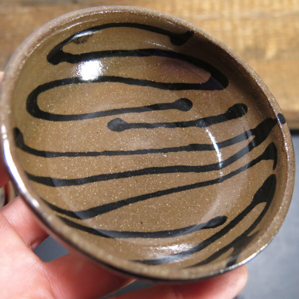 Ceramic sauce bowls with black drizzle decoration and glossy black exterior.