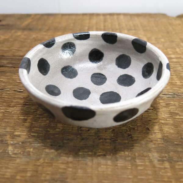 Small ceramic sauce bowl with large black dots on a white background.