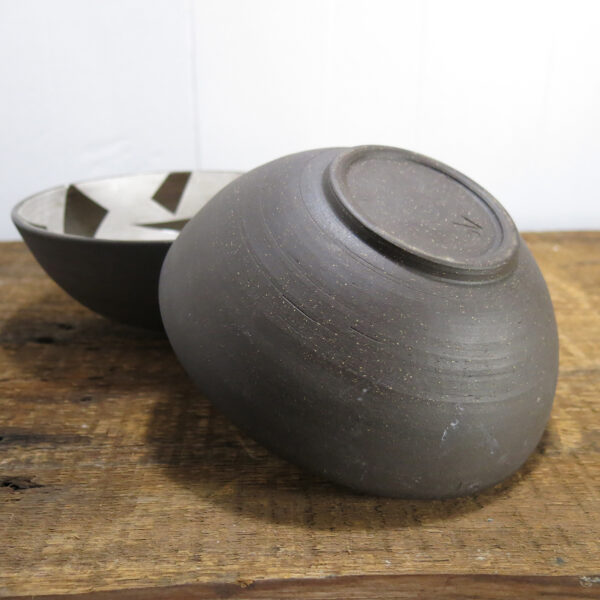Underside of a black clay ceramic bowl.
