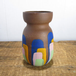 Red clay vase with colorful stripes.