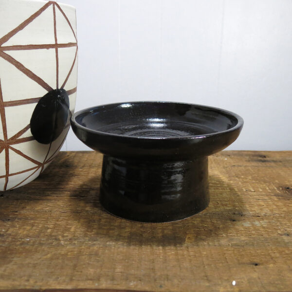 Black ceramic stand with its planter off to the side.