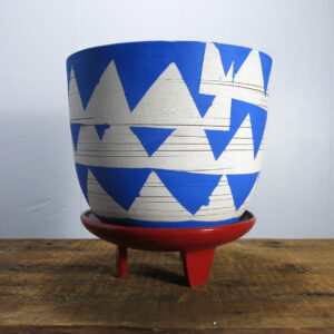 Blue and white ceramic planter on a red, three-legged ceramic stand.