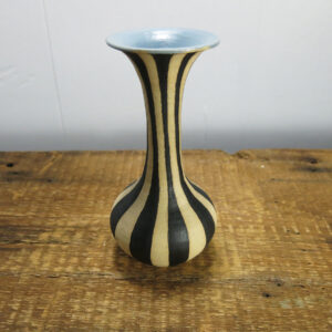 Black striped, cream-colored ceramic vase with a very tall neck and blue inside.