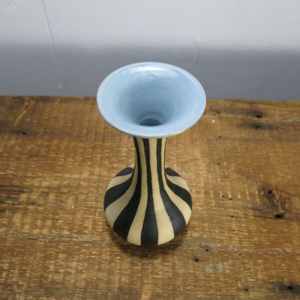 Black striped, cream-colored ceramic vase with a very tall neck and blue inside. Photograph taken from above to show the blue inside.