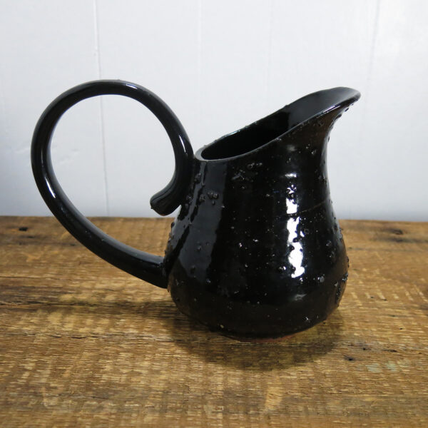 Black ceramic pitcher with a large handle.