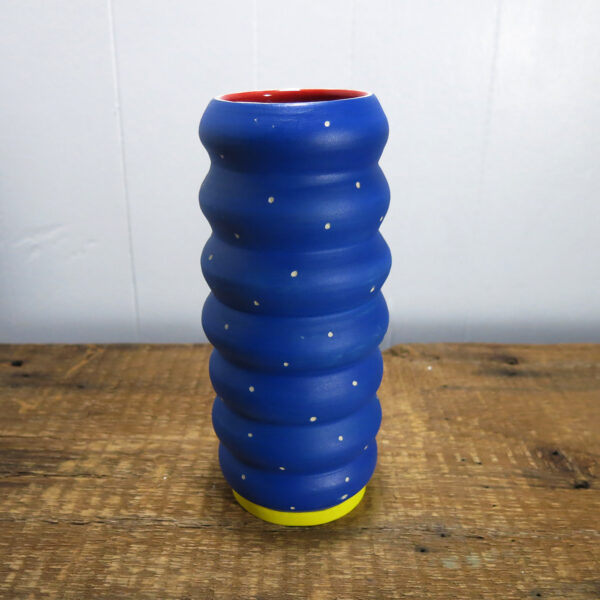 Porcelain vase with undulating walls, painted blue, red, and yellow.