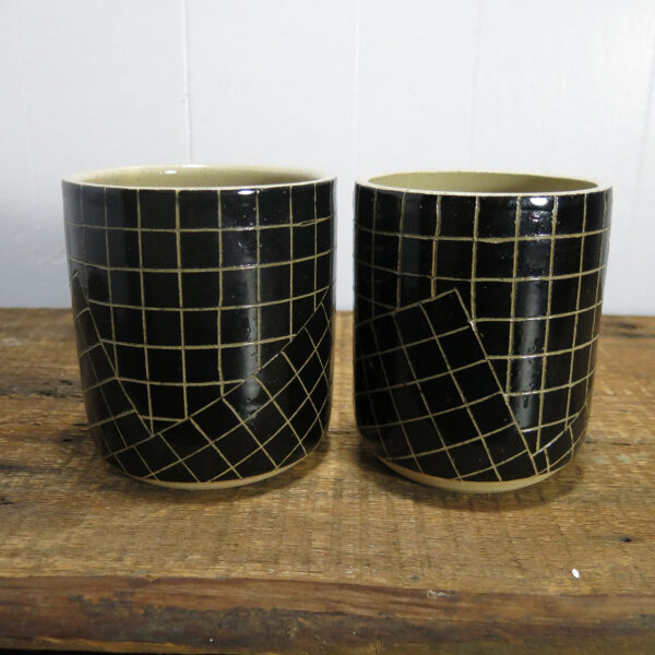 Two ceramic cylinder pots with a black and white grid pattern, made of cream-colored clay.
