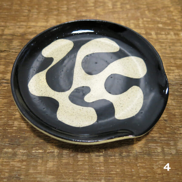 The fourth buff ceramic spoon rest with an organic black decoration.